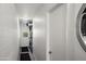 Narrow hallway with brick walls leading to the door, with modern lighting and adjacent laundry unit at 7630 E Pasadena Ave, Scottsdale, AZ 85250
