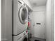 Bright laundry room featuring a stacked washer and dryer with a water heater in the background at 7630 E Pasadena Ave, Scottsdale, AZ 85250