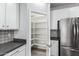 Walk-in pantry featuring ample shelving space, tile backsplash, and open access, next to stainless refrigerator at 7824 S 33Rd Ln, Laveen, AZ 85339
