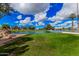 Picturesque golf course view featuring a serene pond, fountain, palm trees, and clear blue skies with white clouds at 8248 E Emelita Ave, Mesa, AZ 85208