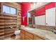 Unique bathroom with rustic wood walls, red accent wall, granite countertop, framed mirror, and tile flooring at 10138 W Oregon Ave, Glendale, AZ 85307