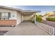 A covered carport provides ample parking space with a white railing and yellow flowers adding a touch of charm at 10620 W Clair Dr, Sun City, AZ 85351