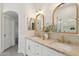 Elegant bathroom with dual sinks, marble countertops, gold fixtures and arched mirrors at 1070 S Amber St, Chandler, AZ 85286