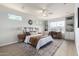 A well-lit main bedroom featuring a ceiling fan, decorative shelving, and a work space with a window view at 11520 W Lizard Ct, Surprise, AZ 85378