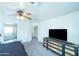 Bright bedroom featuring neutral walls, ceiling fan, a dresser with a television, and carpet floors at 12161 W Flanagan St, Avondale, AZ 85323
