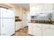 White kitchen with ample cabinet space, granite countertops, and a mosaic backsplash at 13823 N 99Th Dr, Sun City, AZ 85351