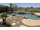 Inviting backyard pool with rock waterfall feature, lush landscaping, and a tranquil setting at 18359 W Sweet Acacia Dr, Goodyear, AZ 85338