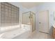 Well-lit bathroom with a soaking tub, a separate shower, and a frosted-glass window at 18415 W Capistrano Ave, Goodyear, AZ 85338