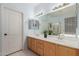 Bathroom featuring a double sink vanity with wooden cabinets and a large mirror at 18415 W Capistrano Ave, Goodyear, AZ 85338