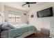 Bedroom featuring a ceiling fan, a large window, and a wall-mounted television at 18415 W Capistrano Ave, Goodyear, AZ 85338