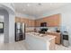Modern kitchen features stainless steel appliances, a central island with a sink, and wood cabinetry at 18415 W Capistrano Ave, Goodyear, AZ 85338