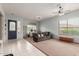 Bright living room with tile floors, a ceiling fan, and a comfortable sofa at 18415 W Capistrano Ave, Goodyear, AZ 85338
