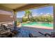 Inviting outdoor living space with covered patio and sparkling pool surrounded by lush landscaping at 18662 W Foothill Dr, Surprise, AZ 85387