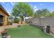 Well-maintained backyard with artificial turf, mature trees, seating, and built-in barbecue area at 19291 E Thornton Rd, Queen Creek, AZ 85142