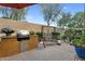 Well-maintained backyard patio featuring a built-in grill, swing, and manicured landscaping against a block wall at 19291 E Thornton Rd, Queen Creek, AZ 85142