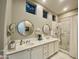 Bright bathroom featuring a double vanity, round mirrors, and a walk-in shower with marble tile at 2042 W Periwinkle Way, Chandler, AZ 85248