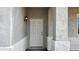 Close-up view of the front door, featuring a classic six-panel design with a wall-mounted lantern sconce at 20435 W Mountain Sage Dr, Buckeye, AZ 85326
