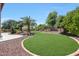 Well-maintained backyard with green grass, decorative rock cover, lush trees, and a patio at 2726 S 160Th Ave, Goodyear, AZ 85338