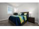 This bedroom has a colorful bedspread, a window with shutters, and a side table with a lamp at 2915 W Night Owl Ln, Phoenix, AZ 85085