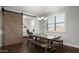 Inviting dining room with a long wooden table, bench seating, plantation shutters, and a view of a sliding barn door at 2915 W Night Owl Ln, Phoenix, AZ 85085
