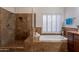 Bathroom showcasing a tiled shower, soaking tub, and plantation shutters at 31017 N 41St Pl, Cave Creek, AZ 85331