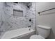 White tiled bathroom with a tub, shower, and toilet at 4950 N Miller Rd # 233, Scottsdale, AZ 85251