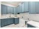 Bright laundry room featuring blue cabinets, white countertops, tile backsplash, and tiled flooring at 5440 E Calle Camelia --, Phoenix, AZ 85018