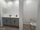 Bright bathroom features a double sink vanity with gray cabinetry and black hardware, next to toilet area at 9544 W Parkway Dr, Tolleson, AZ 85353
