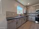 Bright kitchen with stainless steel appliances, sink with window, and gray cabinets at 9544 W Parkway Dr, Tolleson, AZ 85353