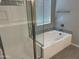 Bathroom showcasing glass-enclosed shower and luxurious soaking tub with tiled surround and modern fixtures at 9963 W Verde Ln, Avondale, AZ 85392