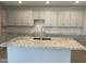 Bright kitchen featuring gray cabinets, granite countertops, and a large island with seating and a sink at 9963 W Verde Ln, Avondale, AZ 85392