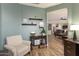 Inviting living room with light chair, wood floors, shelves and open access to other rooms at 15501 W Camino Real Way, Surprise, AZ 85374