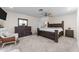 Well-lit bedroom with carpet, ceiling fan, dark wood furniture and neutral colors at 15614 N Lakeforest Dr, Sun City, AZ 85351