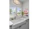 Charming kitchen with a farm sink, white cabinetry, and views of the outdoors through shuttered windows at 15614 N Lakeforest Dr, Sun City, AZ 85351