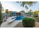Refreshing backyard pool with diving board, lounge chairs, shade umbrellas, and manicured landscaping at 15849 N 46Th Pl, Phoenix, AZ 85032
