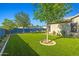 Serene backyard with vibrant artificial turf, mature trees, and a decorative blue fence at 16396 W Fillmore St, Goodyear, AZ 85338