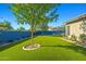 Spacious backyard showcasing lush artificial turf, mature trees, and an attractive blue perimeter fence at 16396 W Fillmore St, Goodyear, AZ 85338