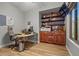 Well-lit home office with built-in wooden shelves, a modern desk, and hardwood floors at 16396 W Fillmore St, Goodyear, AZ 85338