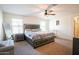 Bright main bedroom with a ceiling fan, carpet floors, a queen-sized bed, and two windows at 16425 W Latham St, Goodyear, AZ 85338