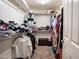 A walk-in closet with plenty of space for folded clothes and clothing hanging on the rod at 16425 W Latham St, Goodyear, AZ 85338