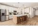 Modern kitchen features a large island with seating, pendant lighting, white cabinetry, and stainless steel appliances at 18231 W Soft Wind Dr, Surprise, AZ 85387