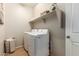 Functional laundry room features modern washer and dryer, open shelving, and efficient layout, simplifying chores at 18231 W Soft Wind Dr, Surprise, AZ 85387