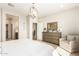 Bright main bedroom featuring neutral tones, stylish light fixture, dresser, and adjacent bathroom for a serene retreat at 18231 W Soft Wind Dr, Surprise, AZ 85387
