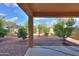 A covered patio overlooking a spacious backyard with desert landscaping and mature trees at 19321 N Tara Lane Ln, Maricopa, AZ 85138