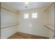 A spacious walk-in closet with wood floors, open shelving, and natural light from windows at 19321 N Tara Lane Ln, Maricopa, AZ 85138