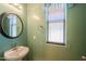 Half bathroom featuring a round mirror, window, and light green paint at 19321 N Tara Lane Ln, Maricopa, AZ 85138