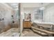 View of bathroom featuring double vanities, stone floors, a claw foot tub on a raised platform, and glass-enclosed shower at 21131 E Excelsior Ave, Queen Creek, AZ 85142