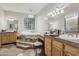 This spacious bathroom features double vanities, stone floors, a claw foot tub on a raised platform, and unique chandeliers at 21131 E Excelsior Ave, Queen Creek, AZ 85142