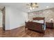 Spacious main bedroom featuring wood floors, brick accent wall, barn door, and a ceiling fan with lighting at 21131 E Excelsior Ave, Queen Creek, AZ 85142