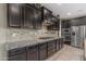 Modern kitchen featuring dark wood cabinetry, granite countertops, stainless steel appliances, and tiled backsplash at 2148 W Angelo Way, San Tan Valley, AZ 85144